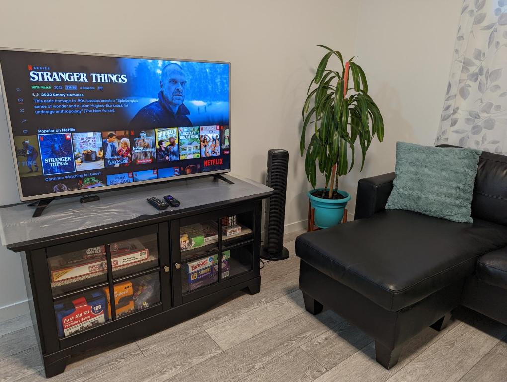 uma sala de estar com um sofá e uma televisão de ecrã plano em Livingston Howse Haven - A simple & cozy private two-bedroom basement suite with free parking em Calgary