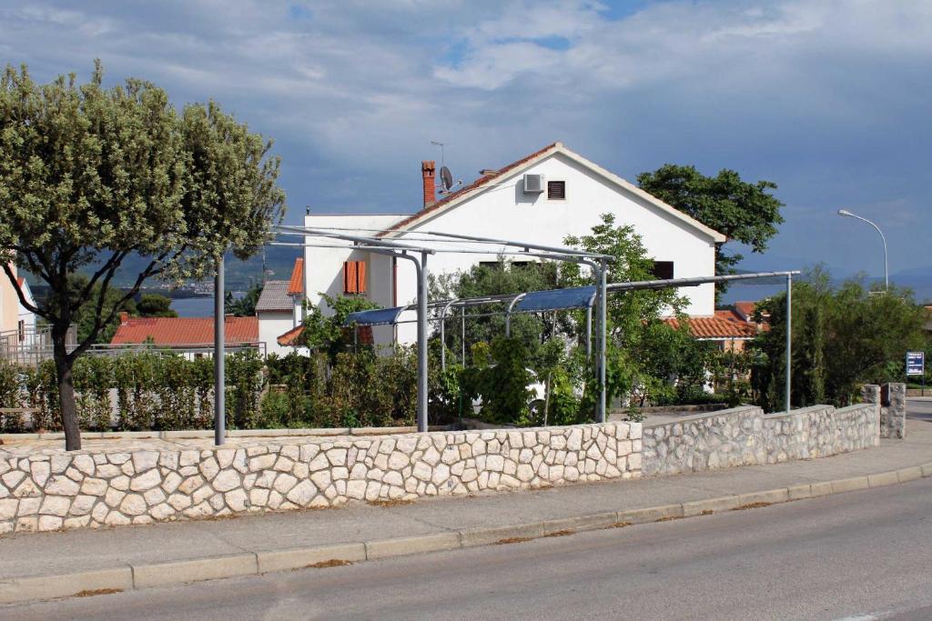 a fence on a stone wall in front of a house at Studio Krk 3231a in Vrh