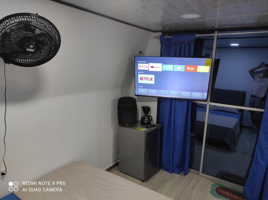 Habitación con cama, TV y ventilador. en Cabañas Mirador La Roca, en Melgar