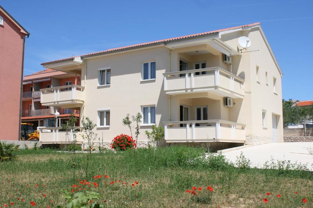 a building with balconies and a field of flowers at Apartments with a parking space Novalja, Pag - 3294 in Novalja