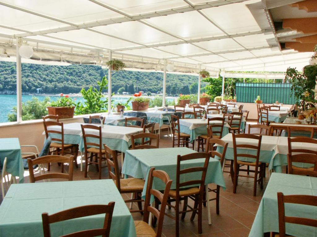 a restaurant with tables and chairs with a view of the water at Rooms by the sea Rabac - Labin - 3016 in Rabac
