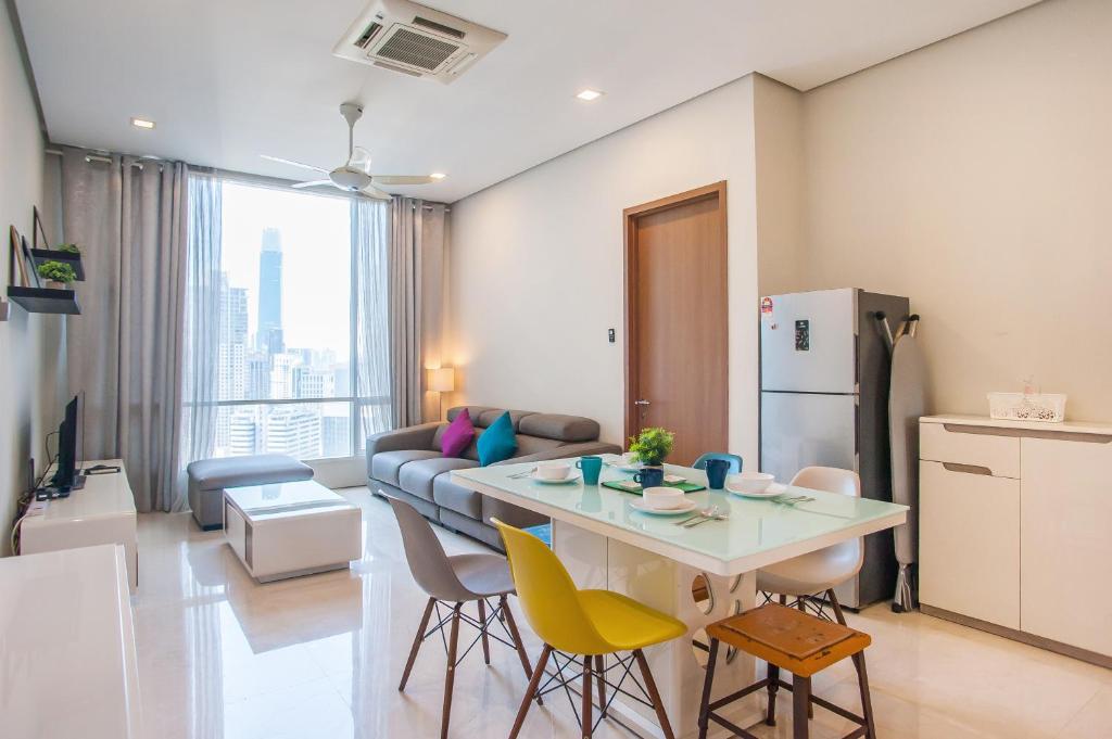 a kitchen and living room with a table and yellow chairs at Soho Suites KLCC by GuestHouse in Kuala Lumpur