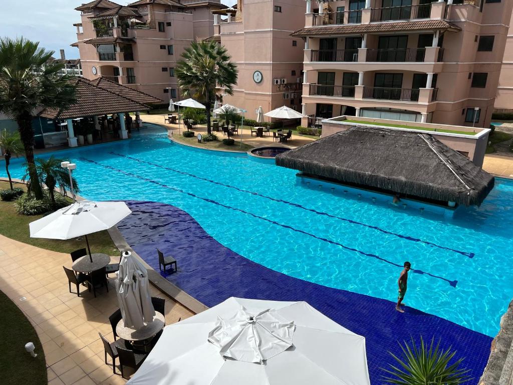 une piscine avec une personne debout devant un bâtiment dans l'établissement Beverly Hills terreo Raul Macedo Neg Imob, à Aquiraz