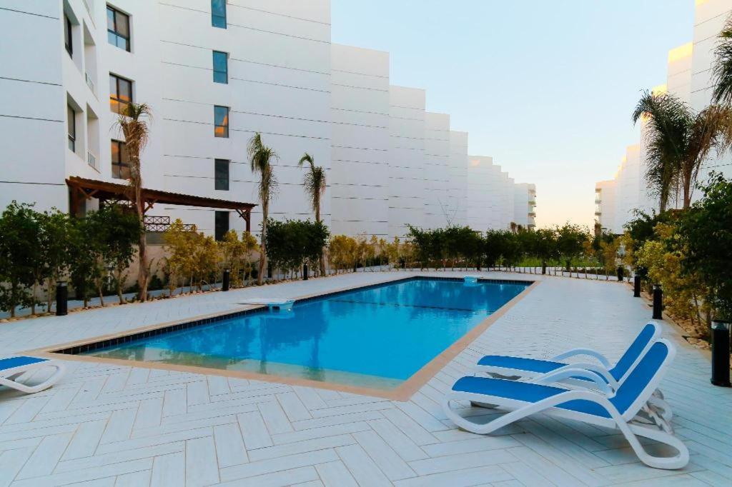 una piscina con 2 tumbonas junto a un edificio en Porto Said apartment, en Port Said