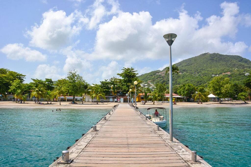 une jetée en bois avec un bateau sur l'eau dans l'établissement Maison du bonheur - 50 m de la plage Anse à l'Ane, à Les Trois-Îlets
