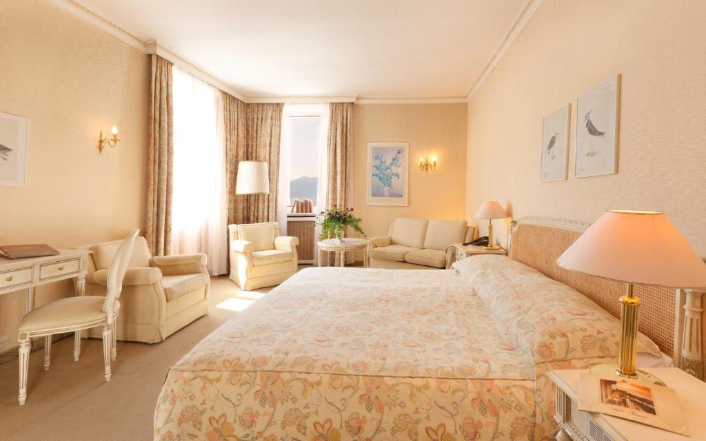 a hotel room with a large bed and a desk at Hotel Tamaro in Ascona