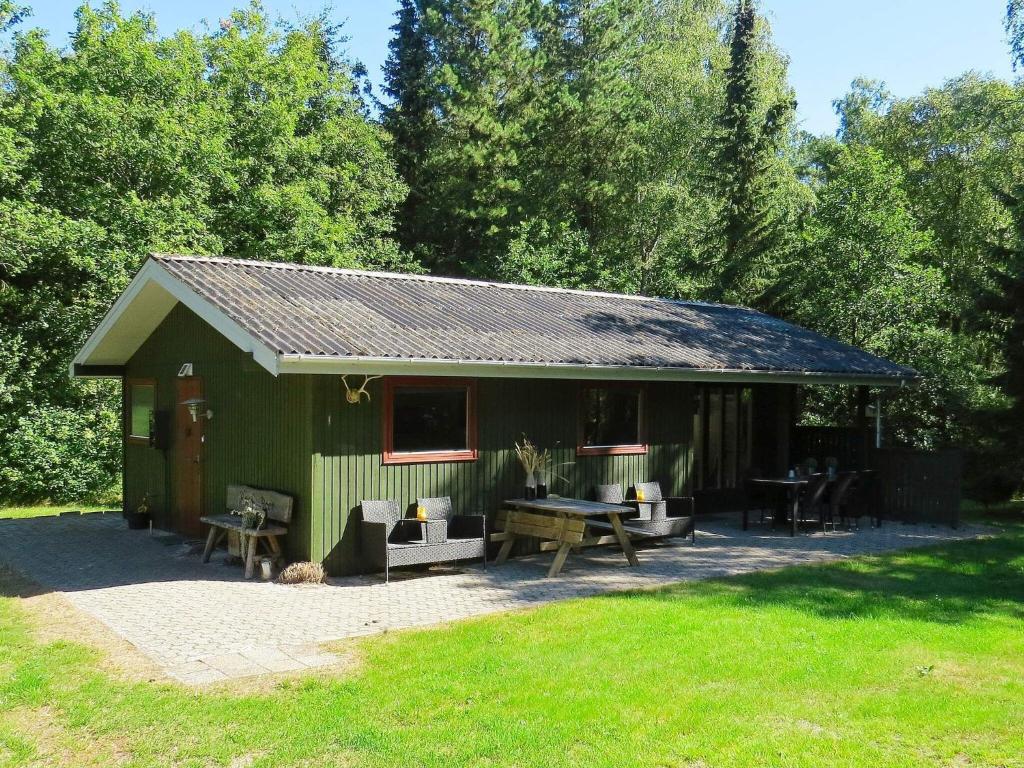 a green shed with a picnic table in the yard at 4 person holiday home in Hals in Hals