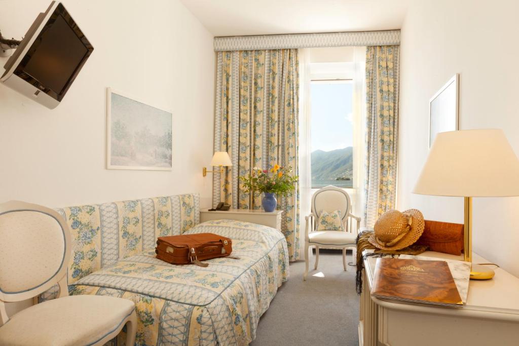 a hotel room with a bed and a couch and a window at Hotel Tamaro in Ascona