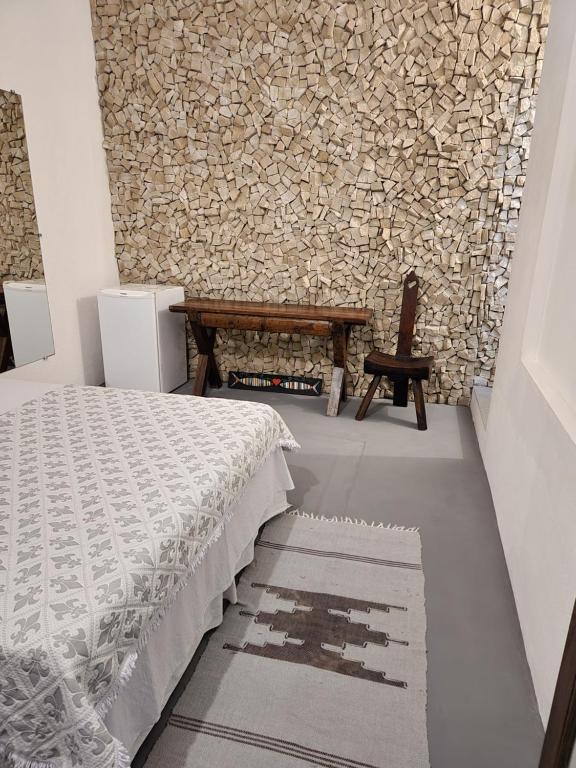 a bedroom with a bed and a bench and a stone wall at Buddha Suítes in Pipa