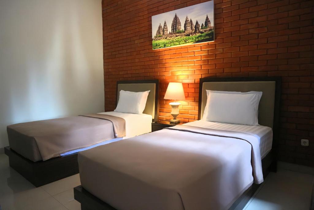 two beds in a room with a brick wall at Omah Watu Homestay in Jetis