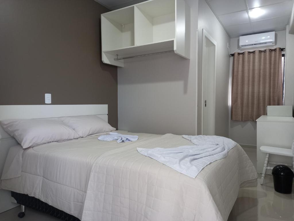 1 dormitorio con 1 cama con colcha blanca en Sognare Hotel, en Caçador