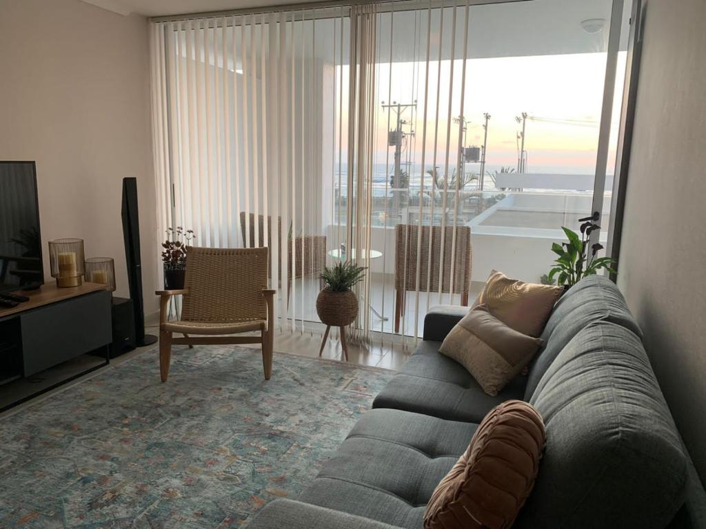 sala de estar con sofá y sala de estar con vistas. en Departamento frente al mar en Arica en Arica