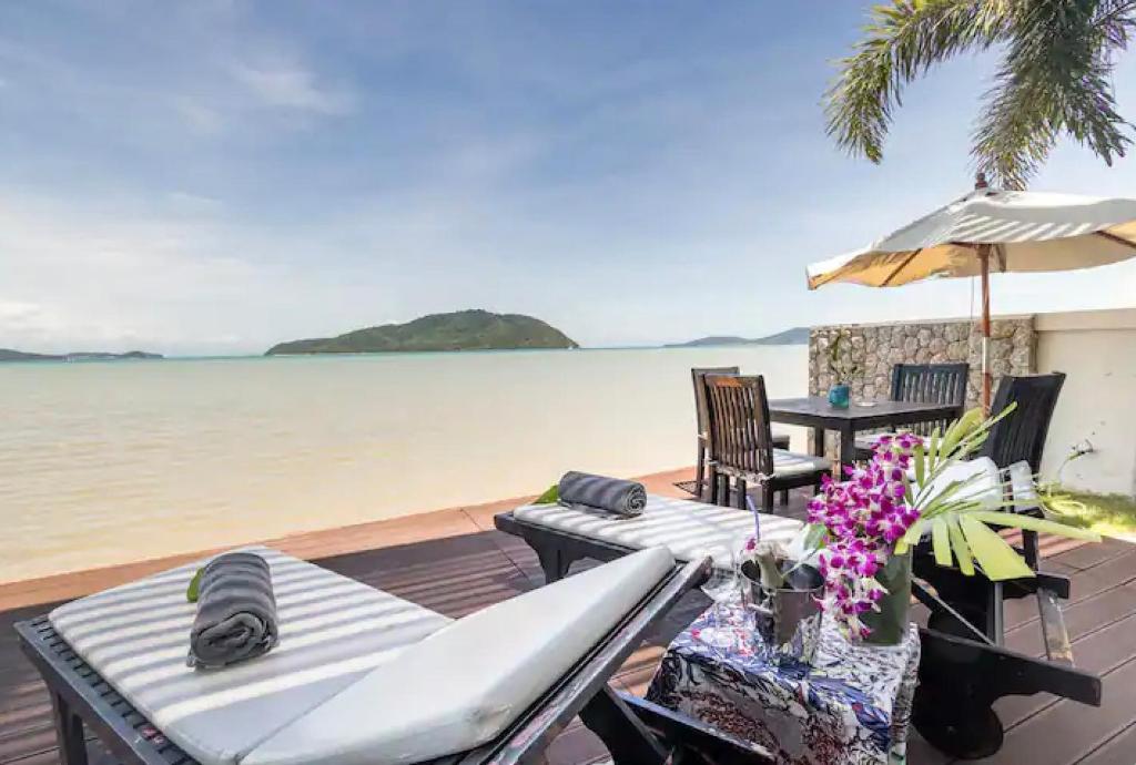 a deck with chairs and an umbrella and the water at Raya Beachloft in Rawai Beach