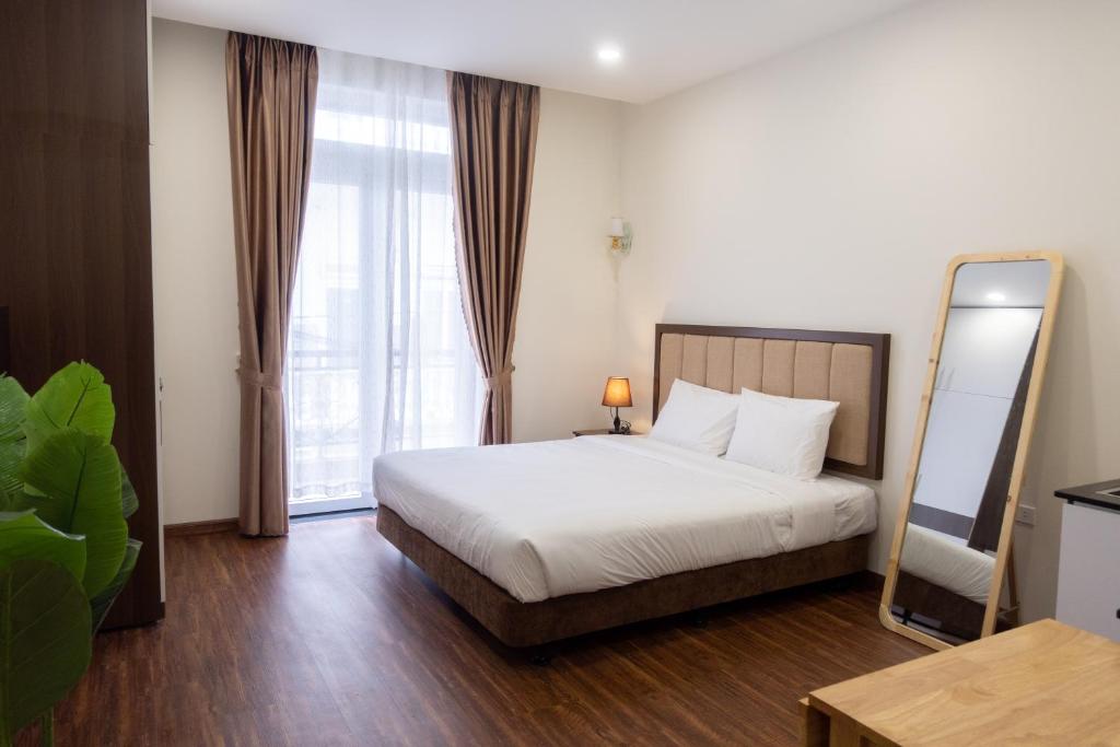 a bedroom with a bed and a large window at Dalat Blanc Hotel & Apartment in Da Thanh