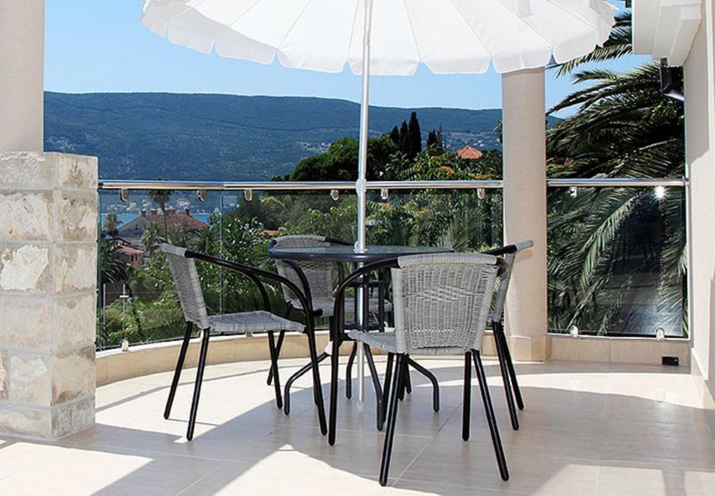 a table and chairs on a balcony with an umbrella at Swiss Residence Montenegro in Herceg-Novi