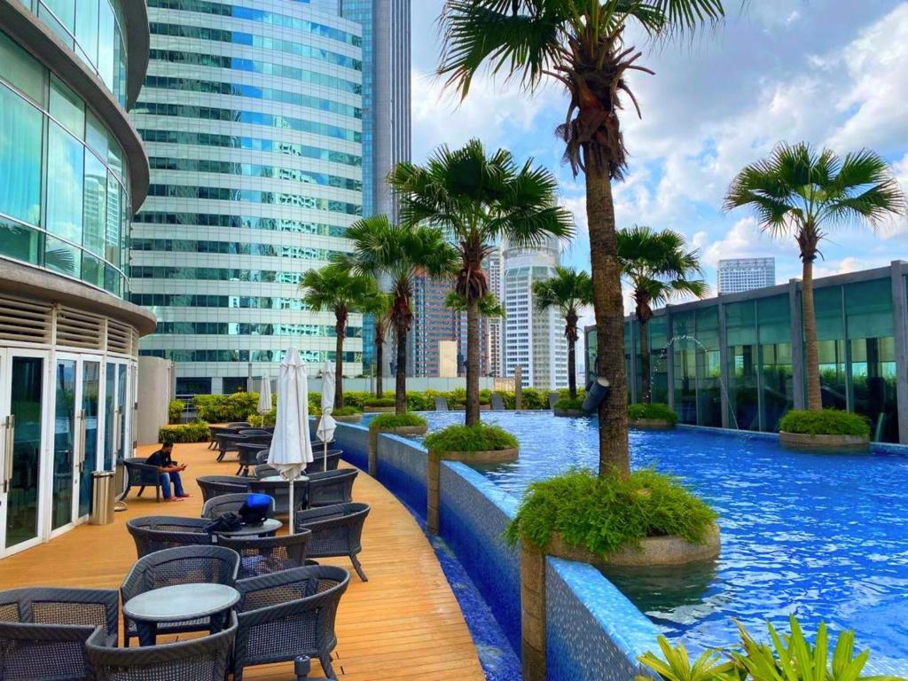 a pool in a building with palm trees and chairs at Vortex Suites KLCC Kuala Lumpur in Kuala Lumpur