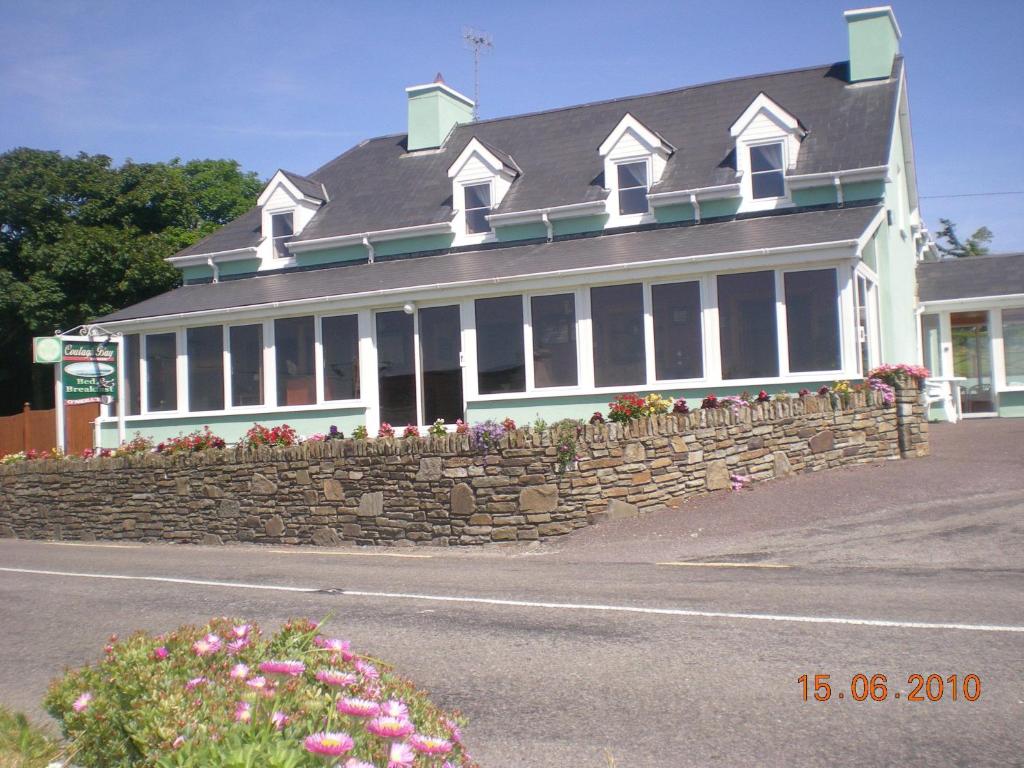 ein großes weißes Gebäude mit einer Steinmauer in der Unterkunft Coulagh Bay House in Eyeries
