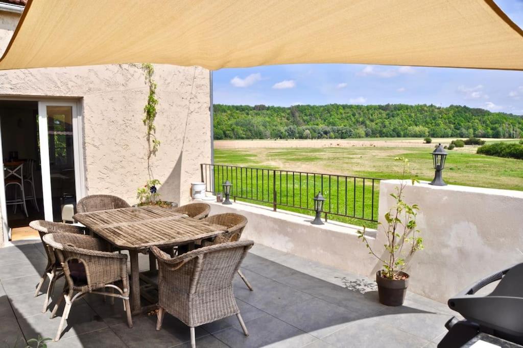 un patio con mesa y sillas y vistas a un campo en confortable maison familiale à l'entrée du village médiéval, en Noyers-sur-Serein
