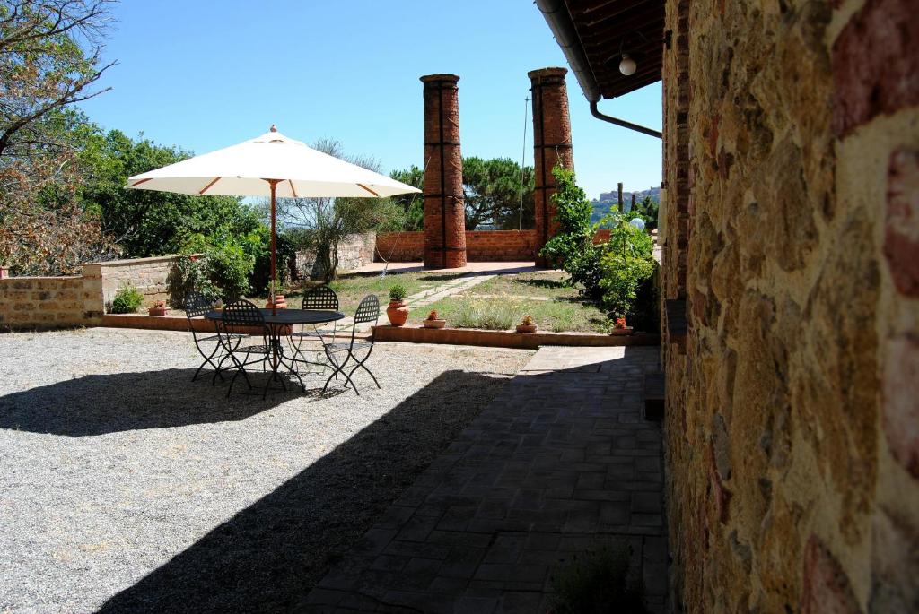 eine Terrasse mit einem Tisch und einem Sonnenschirm in der Unterkunft Agriturismo La Fornace di Poggiano in Montepulciano