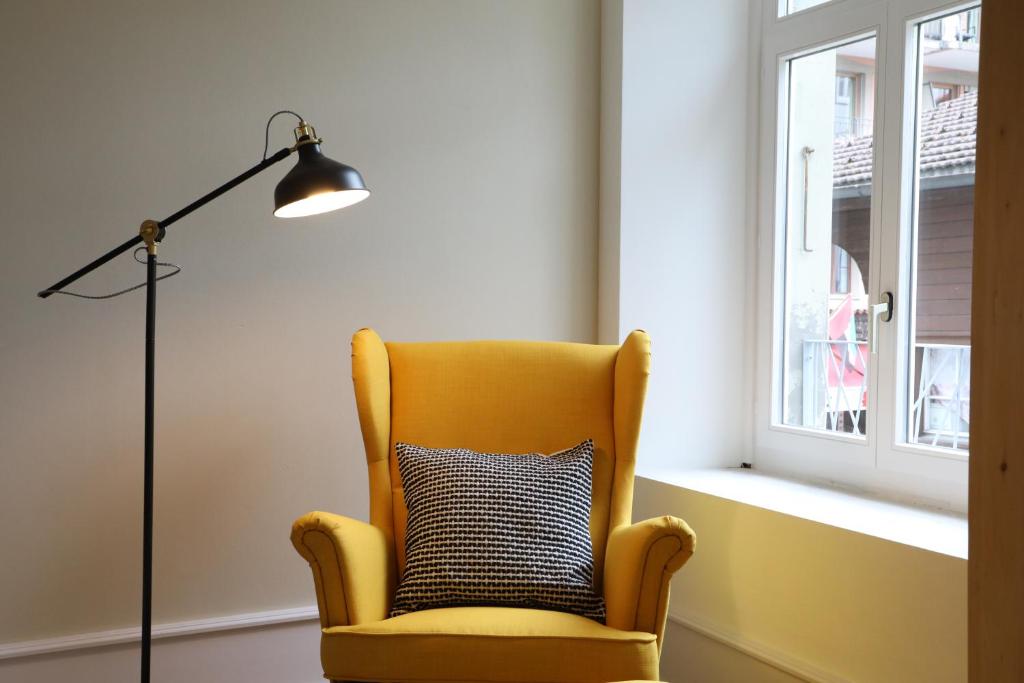 una sedia gialla seduta accanto a una lampada a pavimento di City Center Apartment a Interlaken