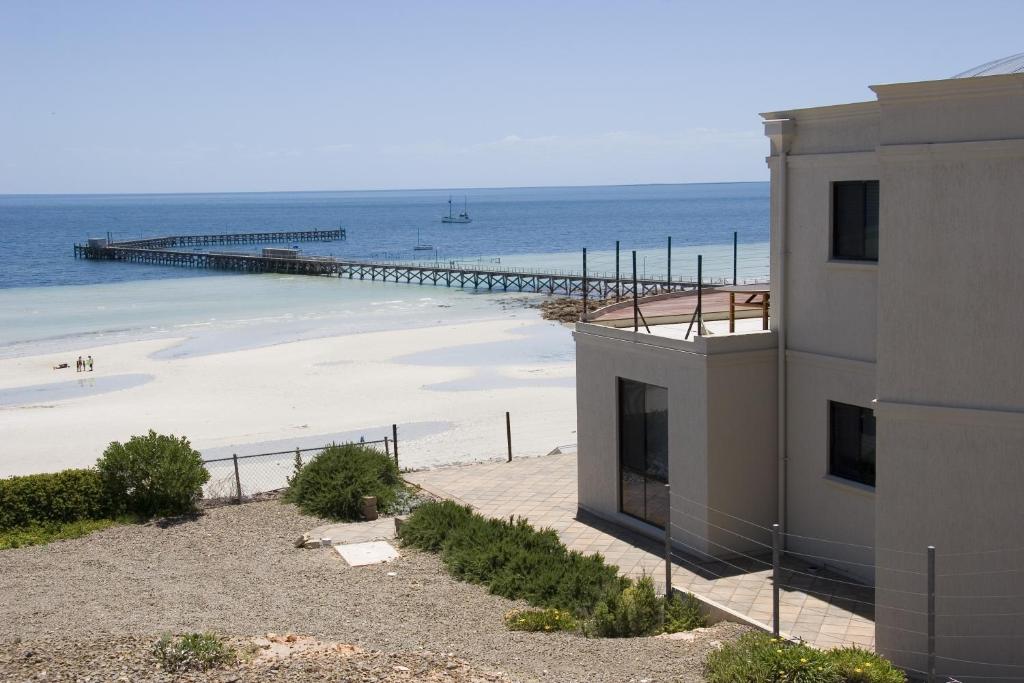 ein Gebäude neben einem Strand mit einem Pier in der Unterkunft Cliff House Beachfront Villas in Moonta