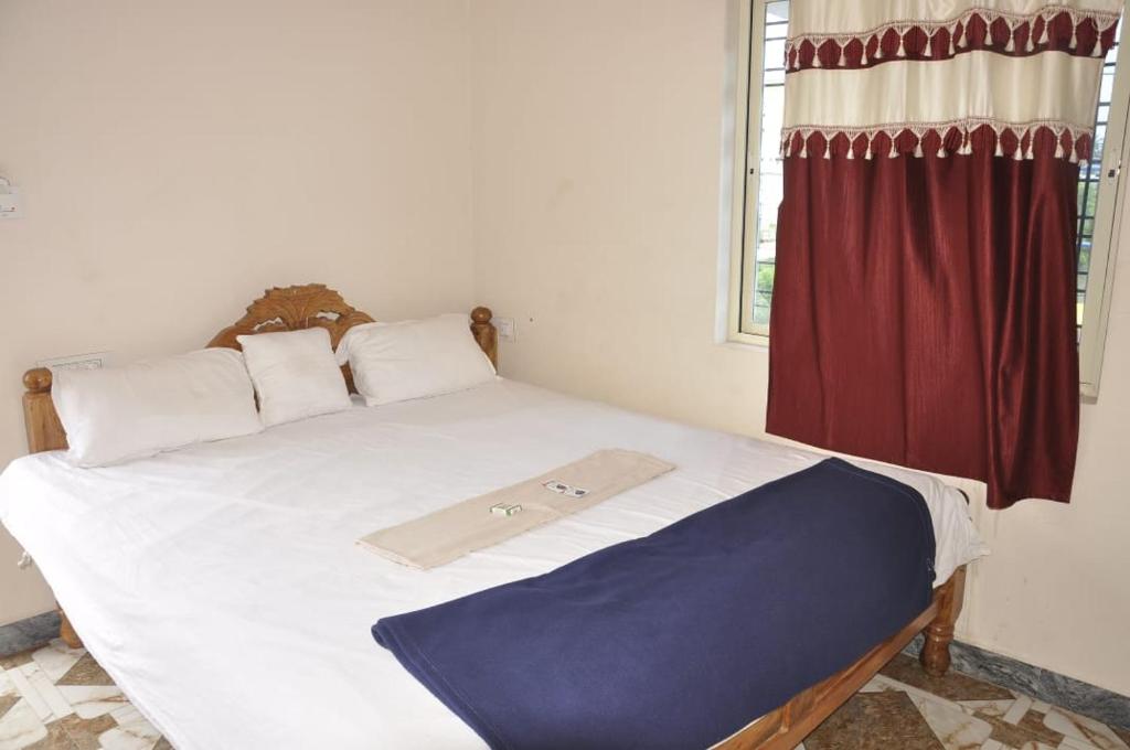 Bett in einem Zimmer mit einem roten Vorhang in der Unterkunft Sanjay Homestay New Hampi in Hampi