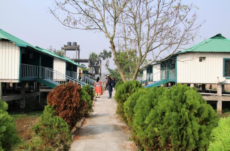 two people walking down a path next to houses at Banani Resort By WB Inn in Gosāba