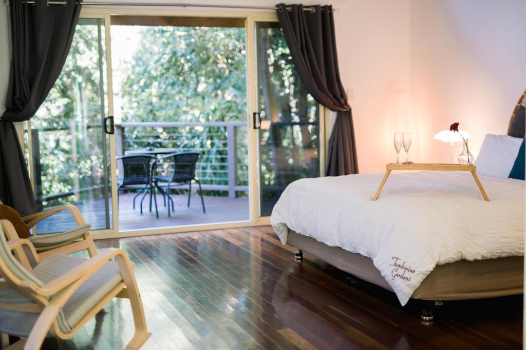 um quarto com uma cama, uma cadeira e uma varanda em Shambala Eco Retreat em Mount Tamborine