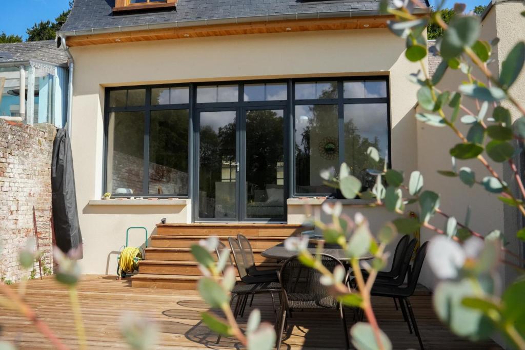 une maison avec une terrasse en bois et des fenêtres noires dans l'établissement Les Hirondelles, gîte de charme avec jardin, 7p, à Saint-Valery-sur-Somme