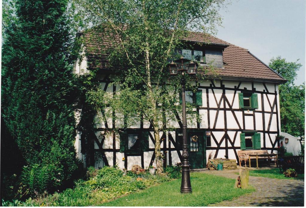 Una casa vieja con un árbol delante. en Historisches Haus Unkelbach, en Irlenborn