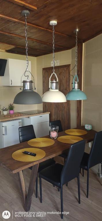 a kitchen with a wooden table with chairs and lights at Apartament Good Night in Nowy Dwór Gdański