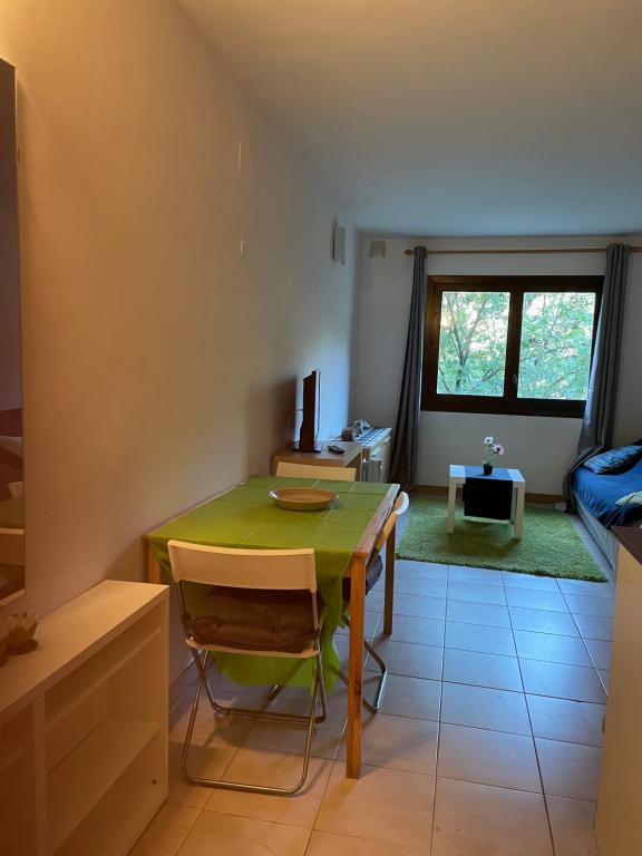 a dining room with a green table and a bedroom at Sol i Neu in Encamp