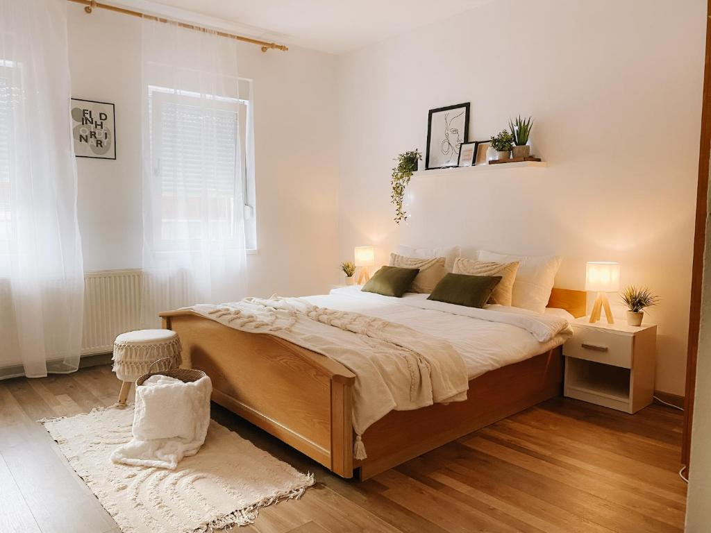- une chambre avec un grand lit aux murs blancs dans l'établissement Cozy 2-Bedroom Boho-Themed Home, à Caransebeş