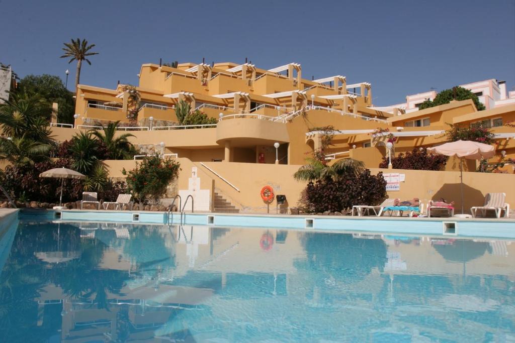 a hotel with a swimming pool in front of a building at Apartamentos Punta Marina by LIVVO in Morro del Jable