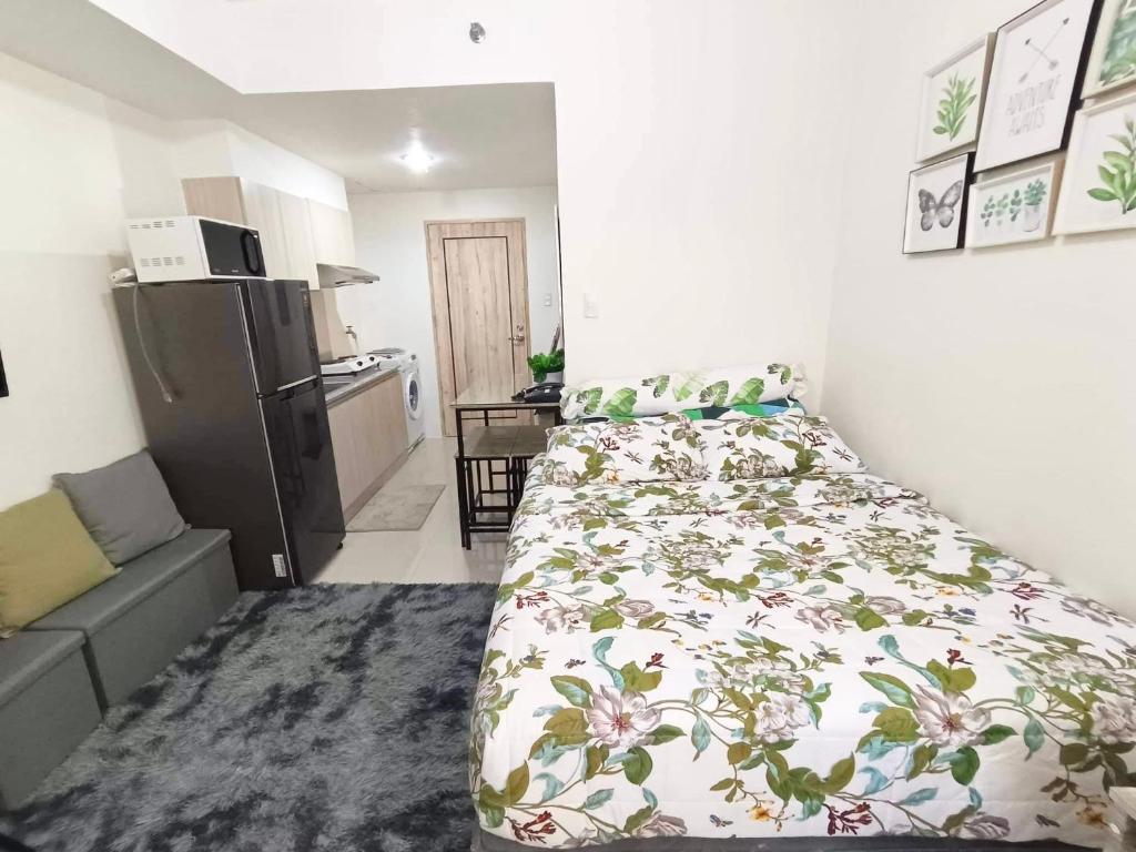 a small bedroom with a bed and a refrigerator at Hola! Condotel @ Inspiria Davao in Davao City