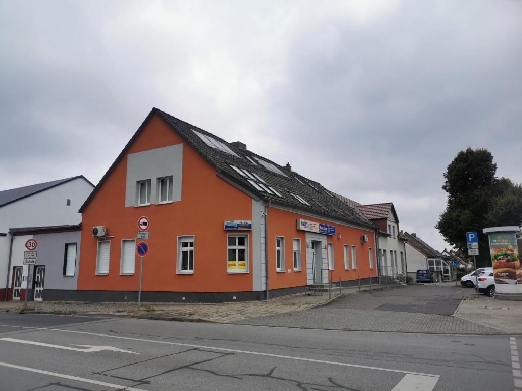 ein orangefarbenes Gebäude an der Straßenseite in der Unterkunft Zimmervermietung Schönfließer Stuben auch für Monteure in Eisenhüttenstadt