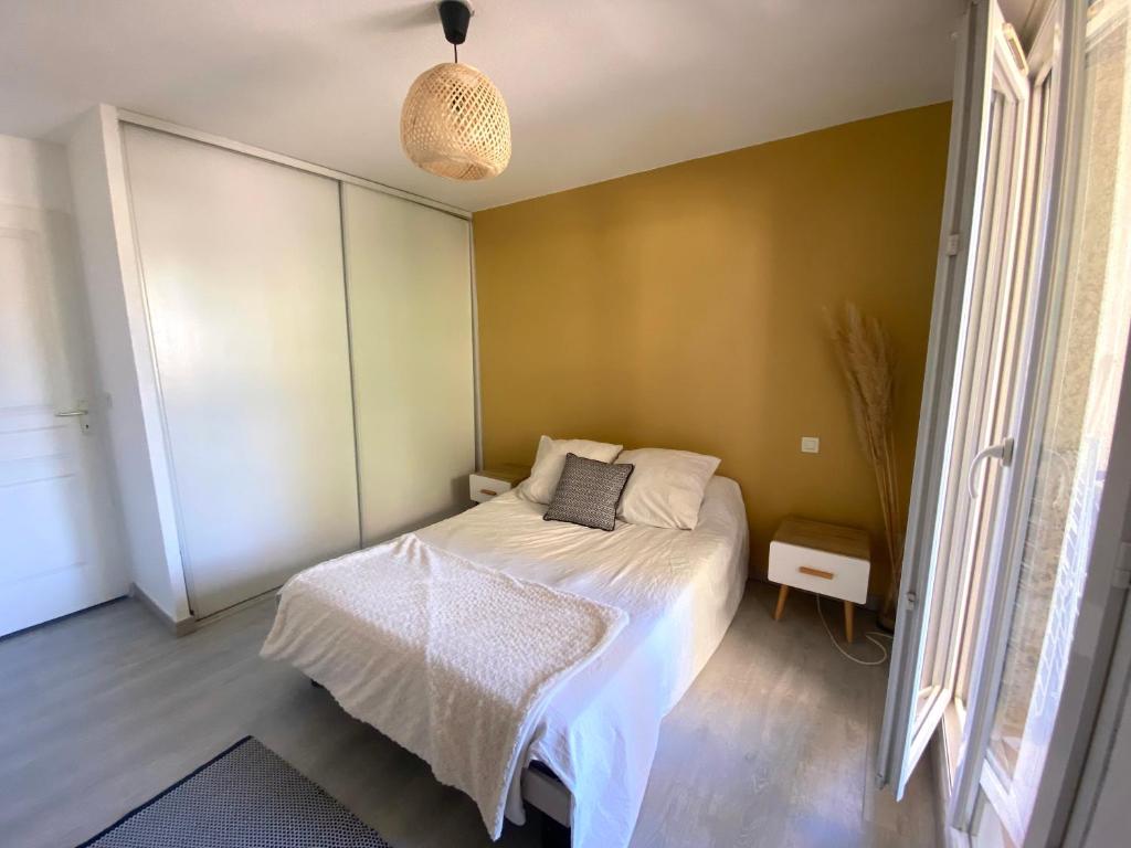a small bedroom with a bed and a pendant light at Centre ville, parking privé in Perpignan