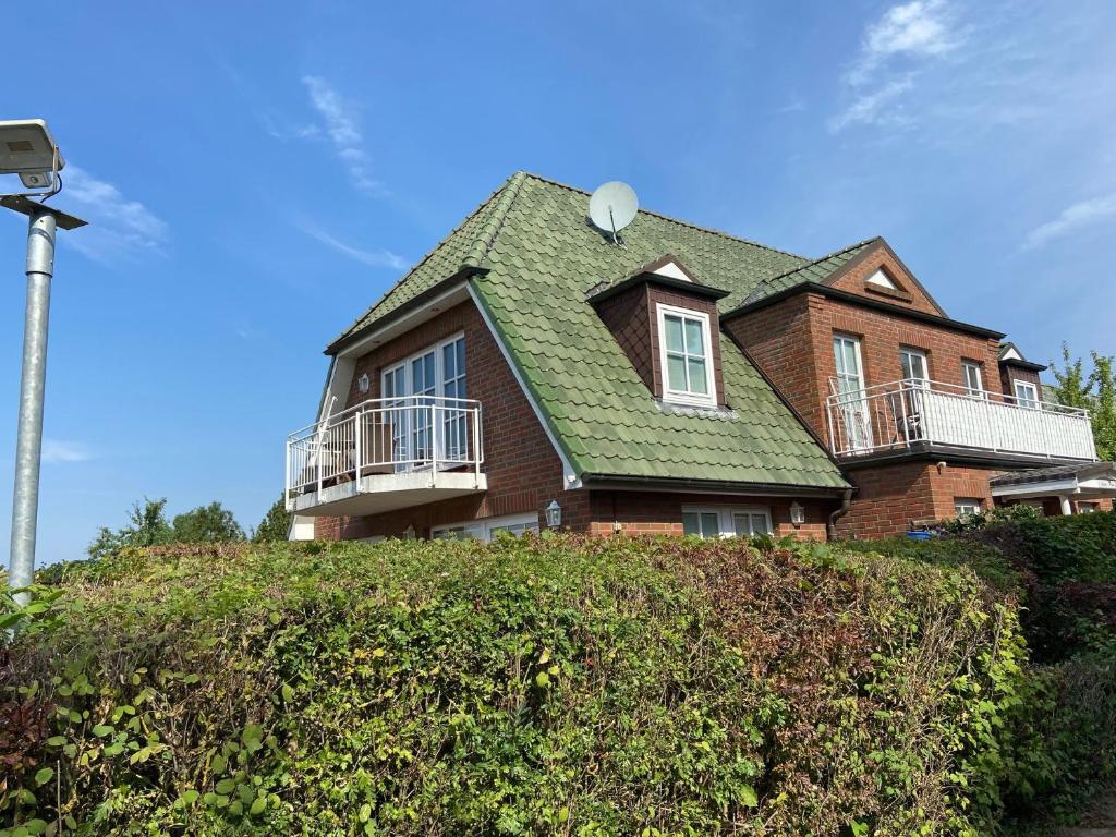 a house with a green roof on top of a hedge at Haus Jenny, Wohnung E3b, Sonne rundum in Boltenhagen