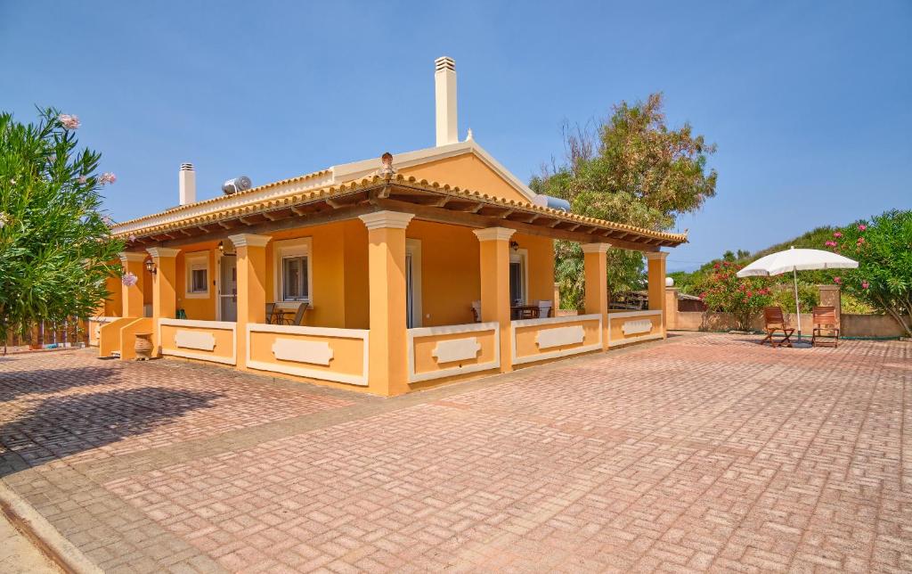 a small yellow building on a brick road at Drosia Beach House Almyros Corfu in Almiros Beach