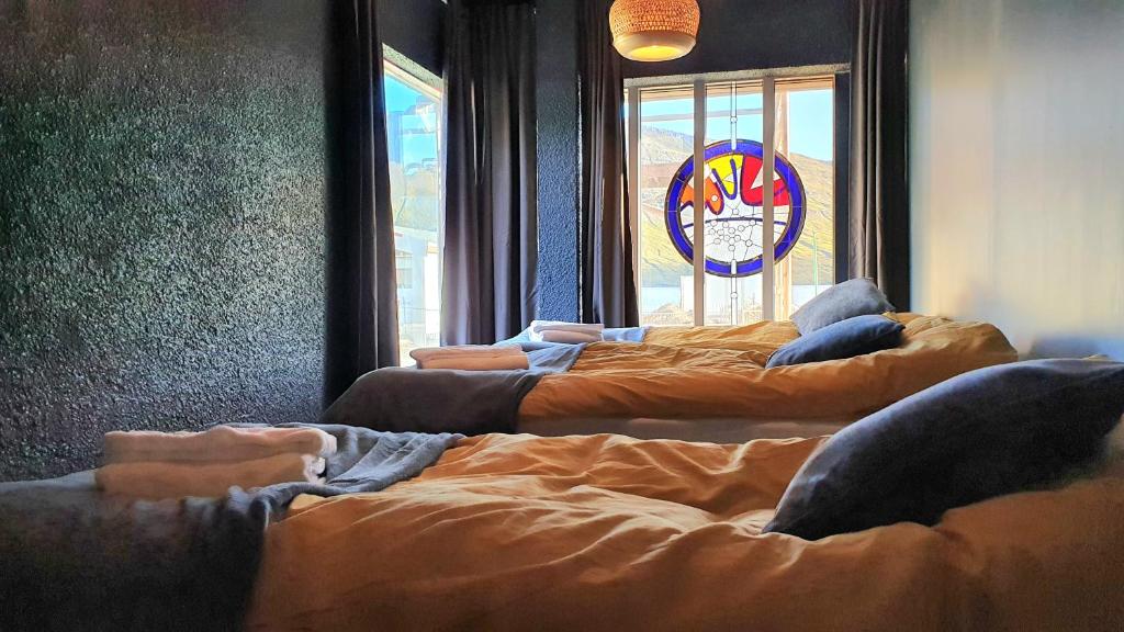 a group of beds in a room with a window at The Bank Sleeping in Neskaupstaður