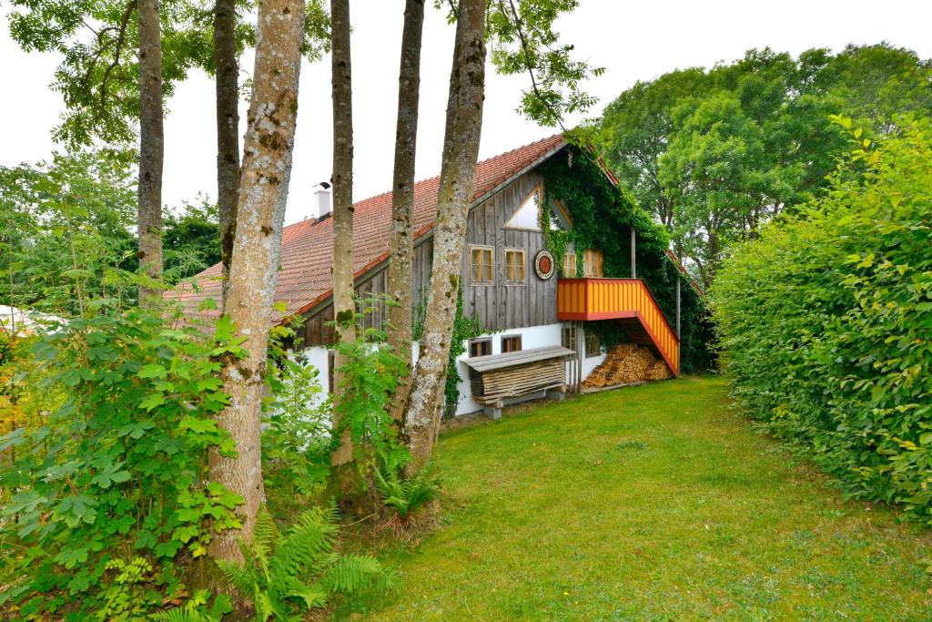 ein Haus mit einem Balkon und einem Garten mit Bäumen in der Unterkunft Hofatelier Menacher in Neureichenau
