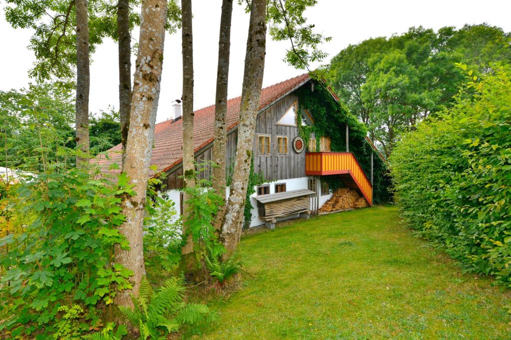 une maison avec un balcon et une cour arborée dans l'établissement Hofatelier Menacher, à Neureichenau