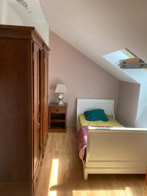 Dormitorio en el ático con cama y mesita de noche en CHEZ HUSNA en Conflans-Sainte-Honorine