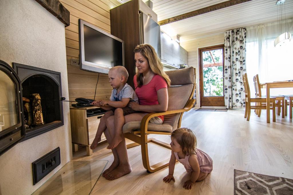 Eine Frau und ein Kind sitzen auf einem Stuhl neben einem Kamin in der Unterkunft Vuokatinmaa Holiday Apartments in Vuokatti