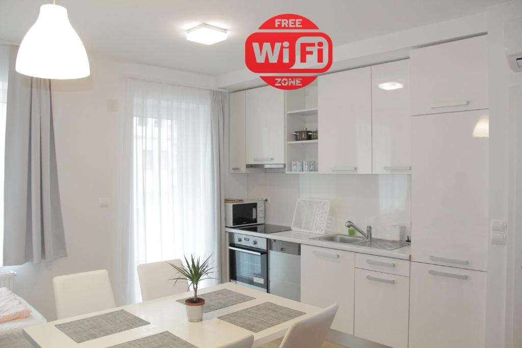 ウィーンにあるベタリアル アパートメンツ S22の白いキャビネット、テーブルと椅子付きのキッチンが備わります。
