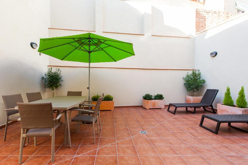 a patio with a table and a green umbrella at Key San Pau House Terrace - Barcelona in Barcelona