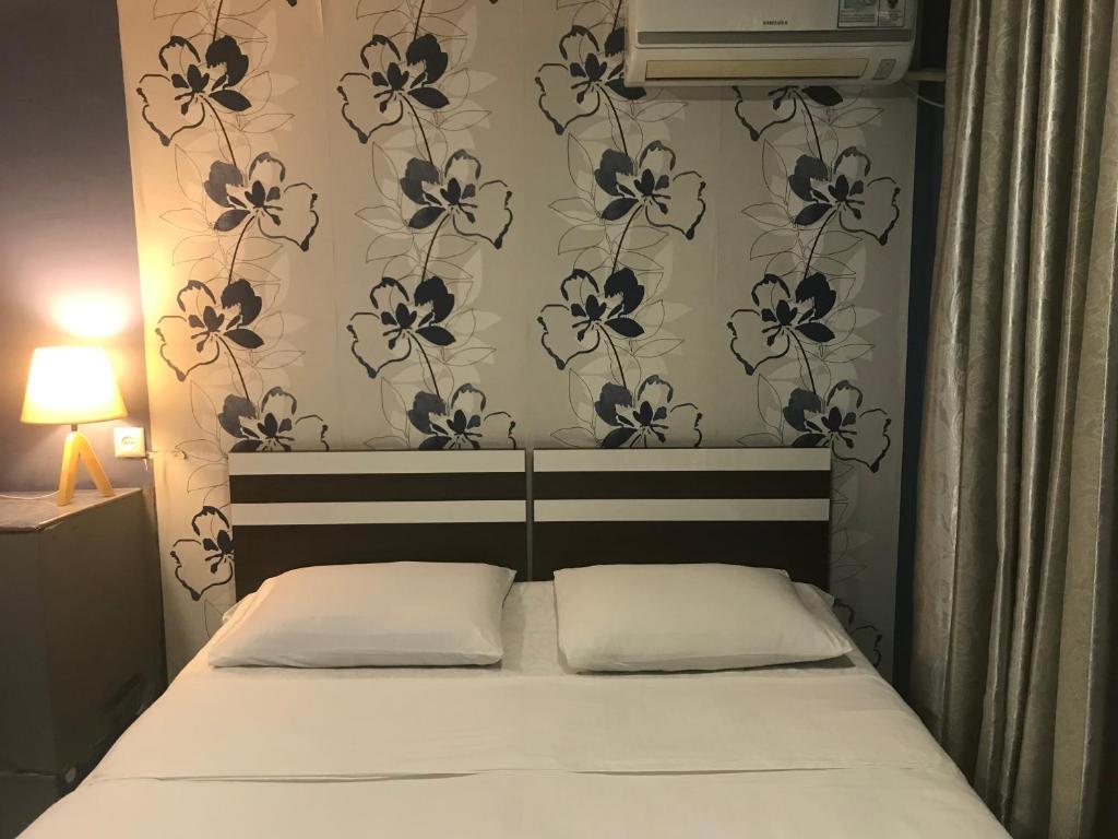1 cama con 2 almohadas en un dormitorio con papel pintado de flores en Meidani Guest house, en Tiflis