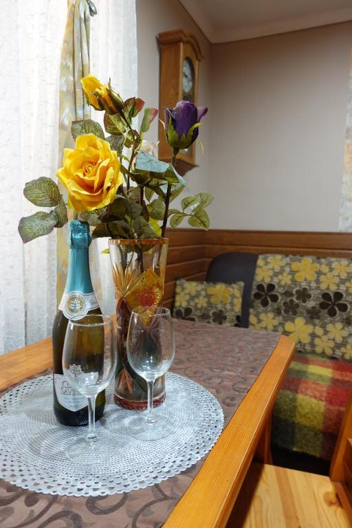 un tavolo con due bicchieri da vino e un vaso con una rosa gialla di Noclegi u Ani a Opatów