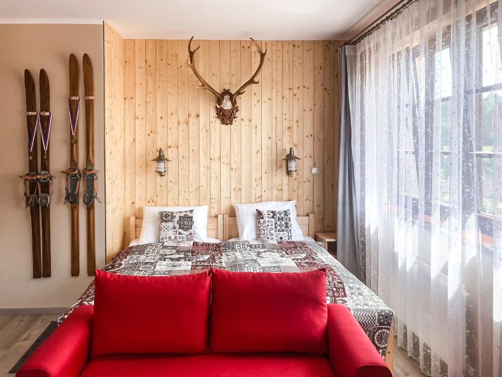 a bedroom with a red couch in front of a bed at Apartman Hubert in Kašperské Hory