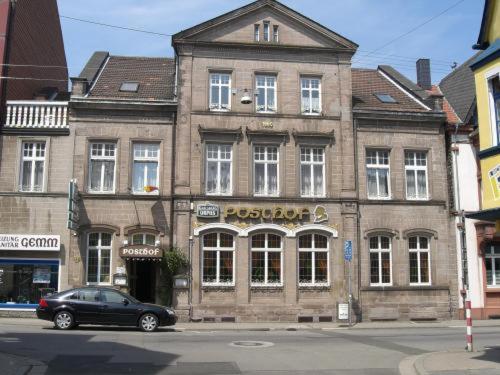 ein vor einem großen Backsteingebäude geparkt in der Unterkunft Hotel Posthof in Sankt Wendel